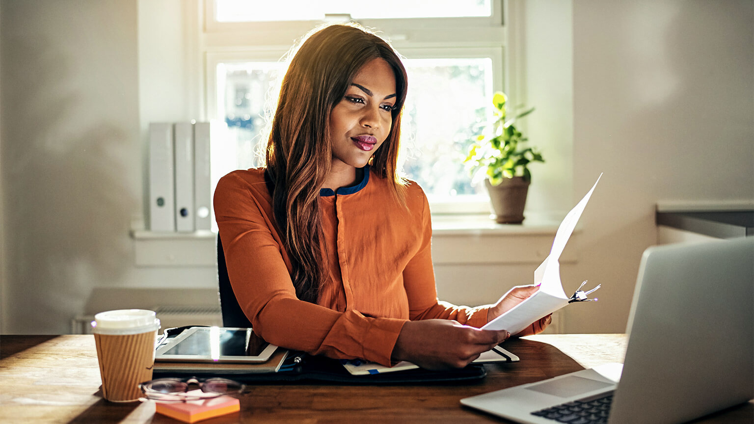 A young professional seated in their home office, reviewing financial statements for a client