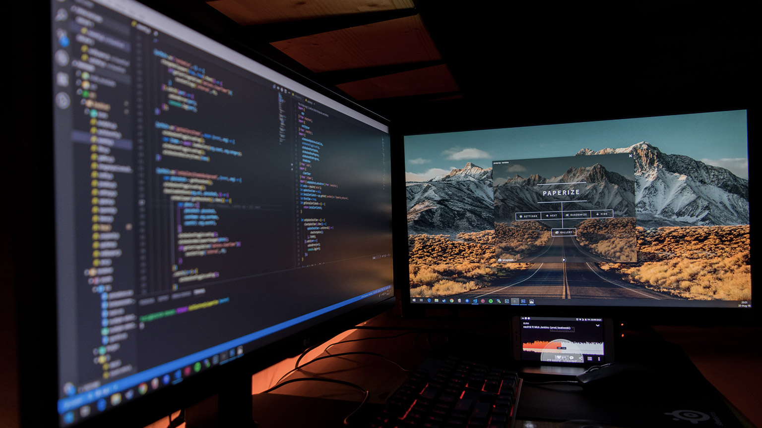 A dual-monitor setup on a desk showing backend and frontend of a website