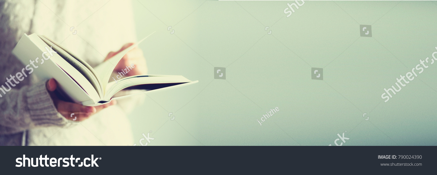 Young girl in white cardigan reading opened book. Copy space. lifestyle and school concept. Banner.