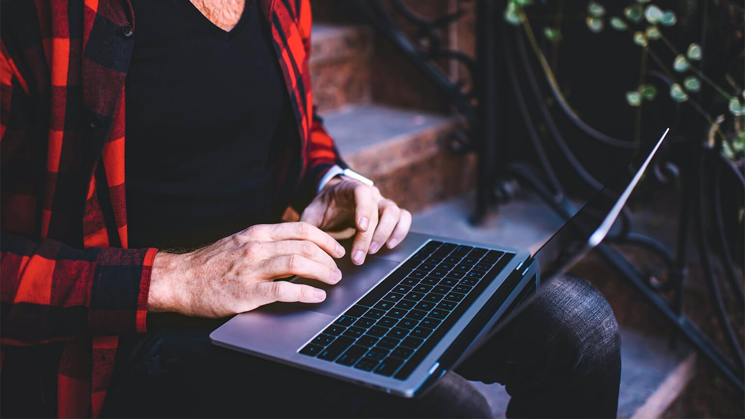 A digital nomad, seated outside, writing some code to deliver the feature they've committed to in their current dev sprint