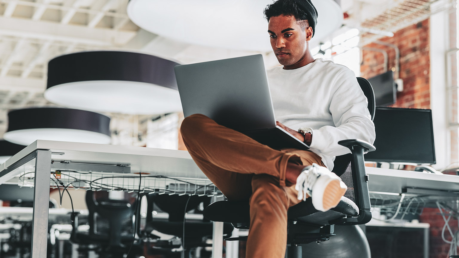 A young programmer working on a project on a laptop in a modern office environment