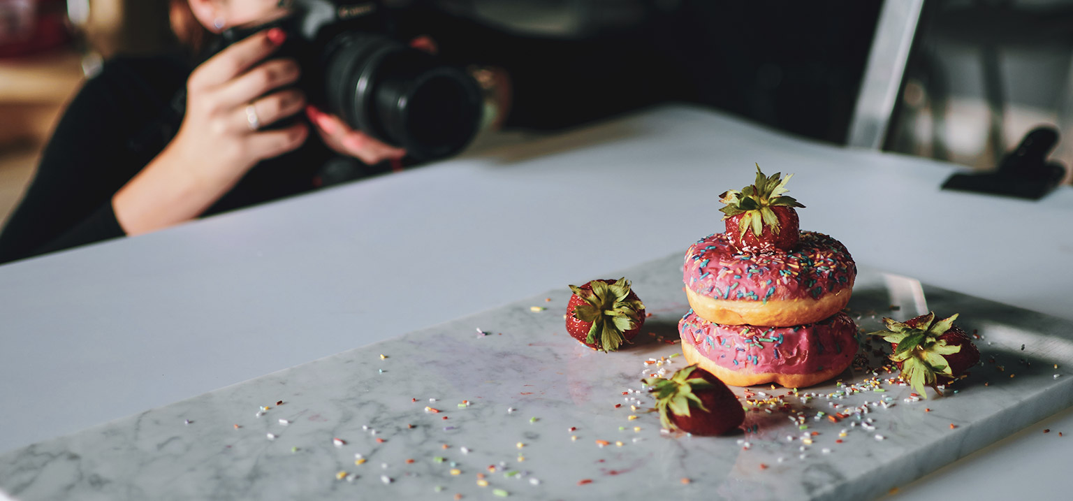 A photographer taking pictures of some yummy donuts