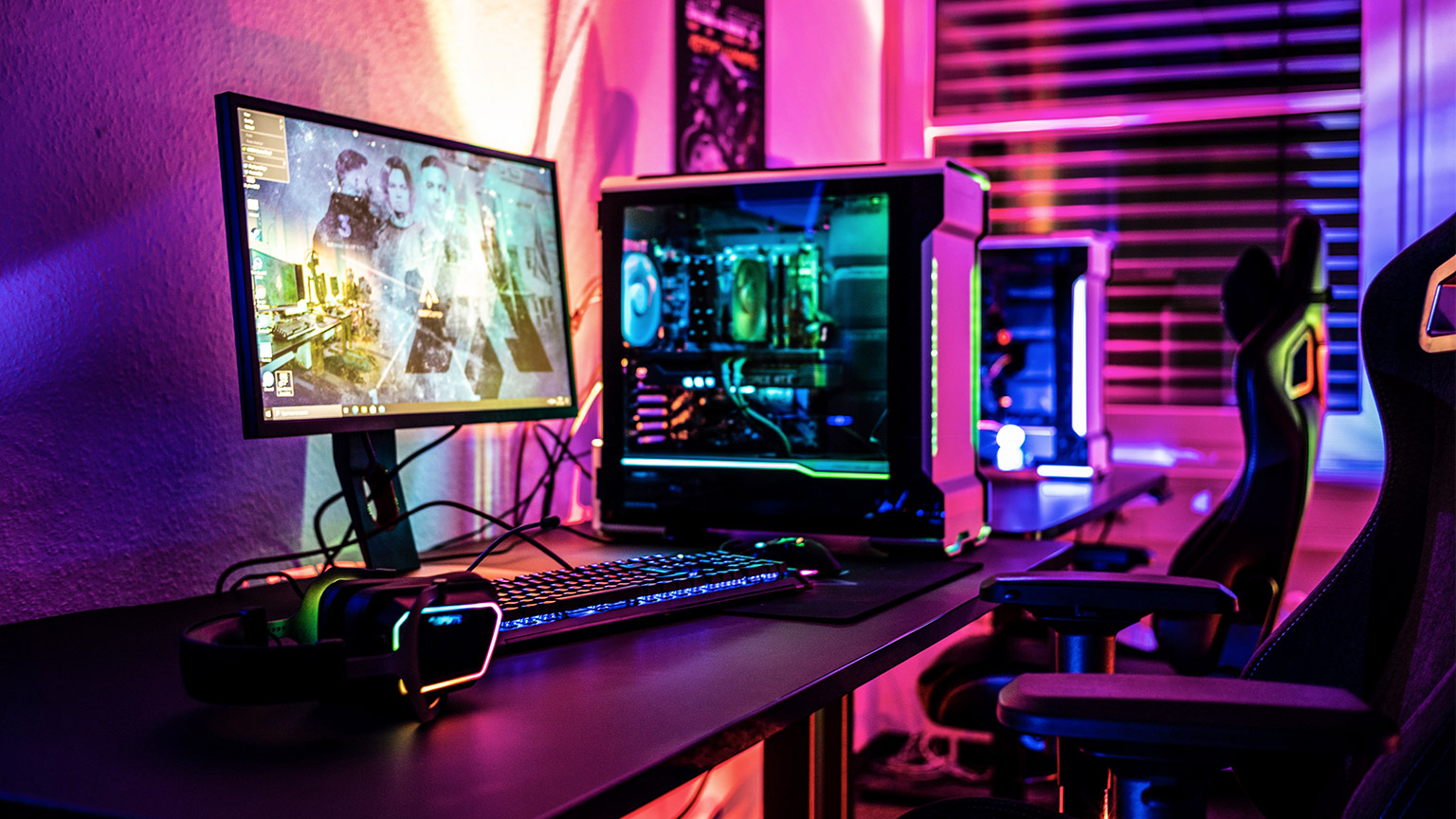 A gaming computer on a desk bathed in various neon colours