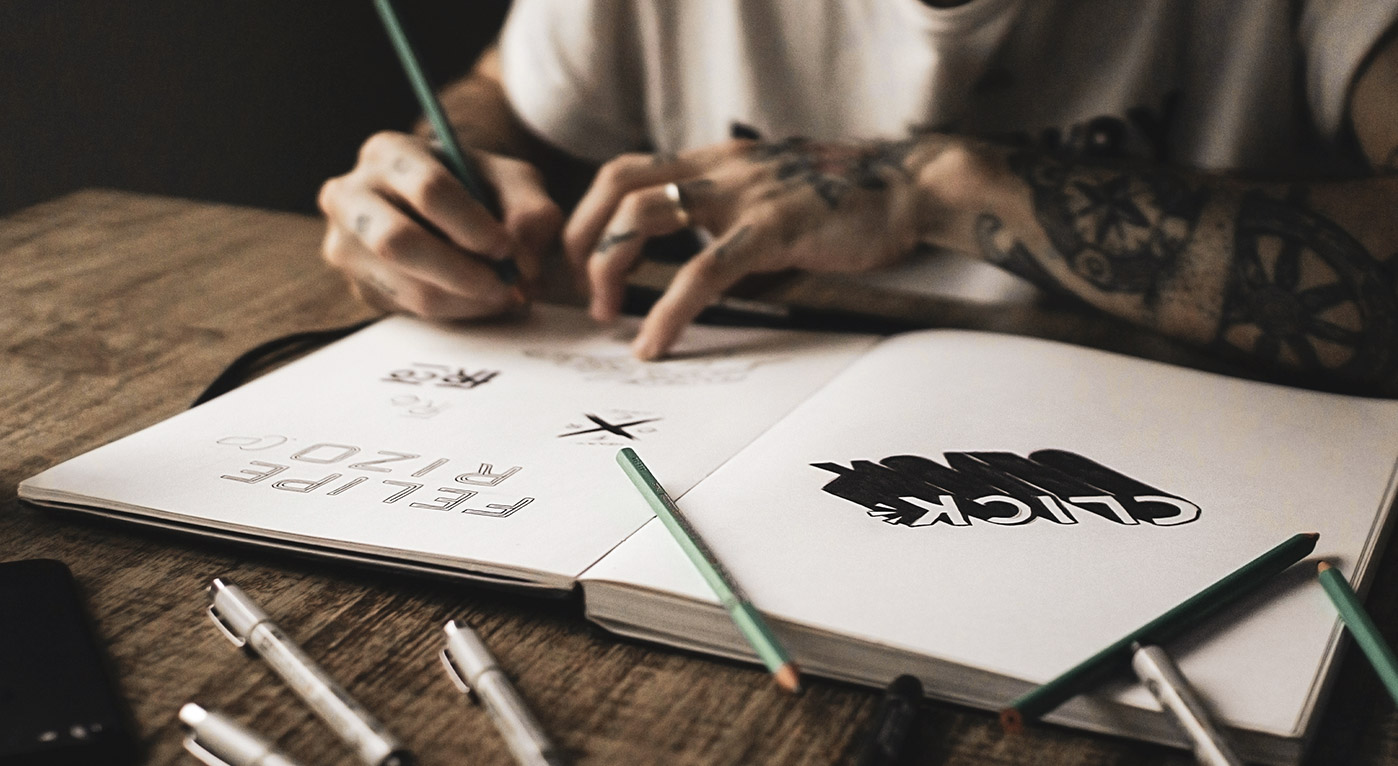 A close view of a designer working on logo ideas on a notepad