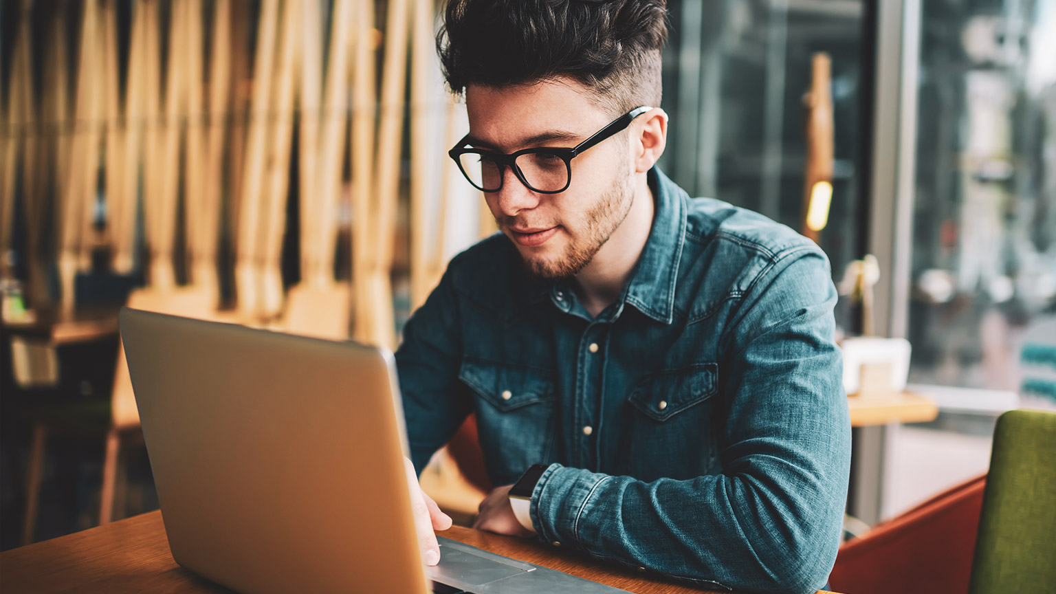 A student sitting in a relaxed environment reading articles on a laptop