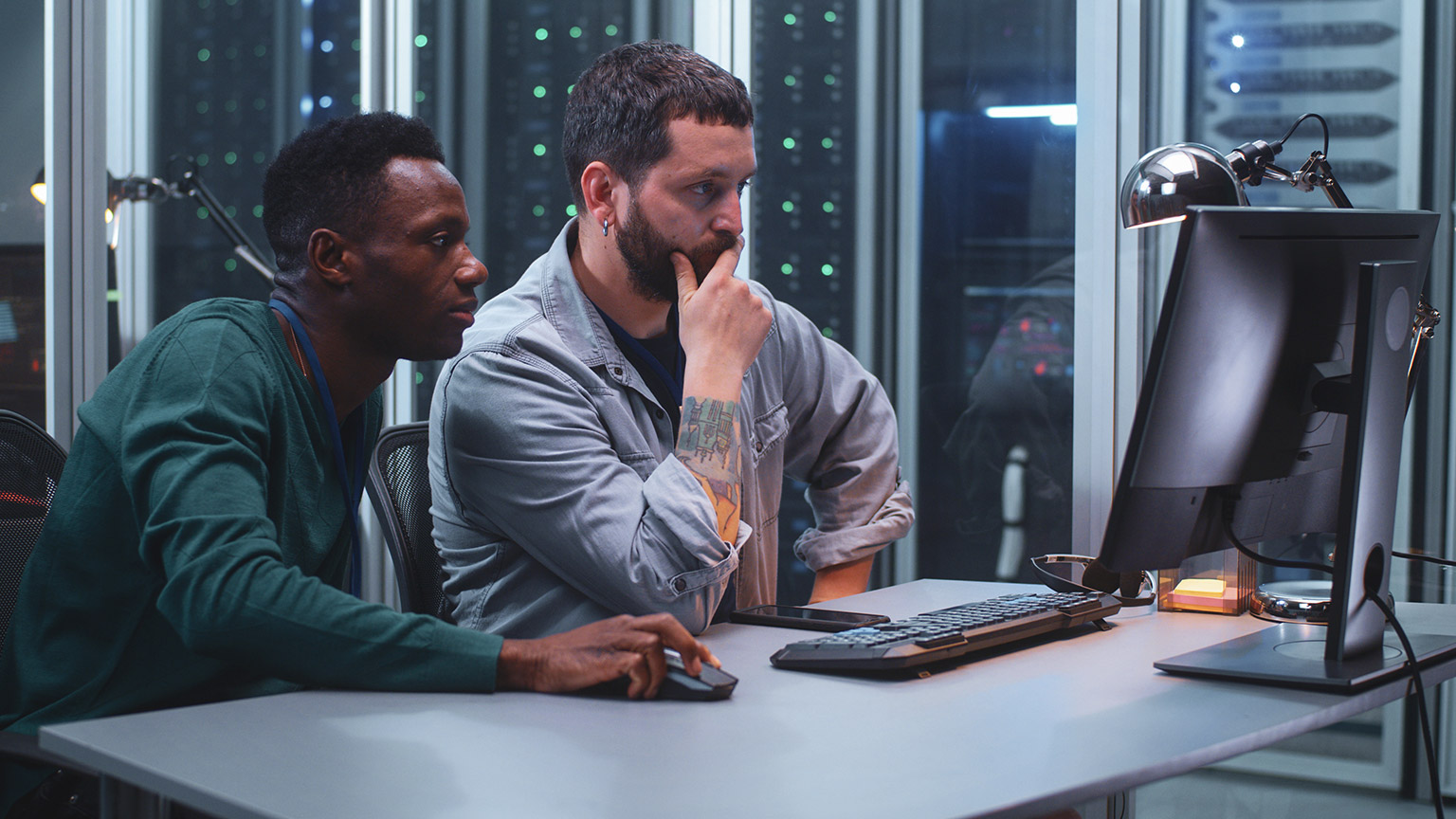 Two IT professionals seated at a desk, diagnosing a network issue