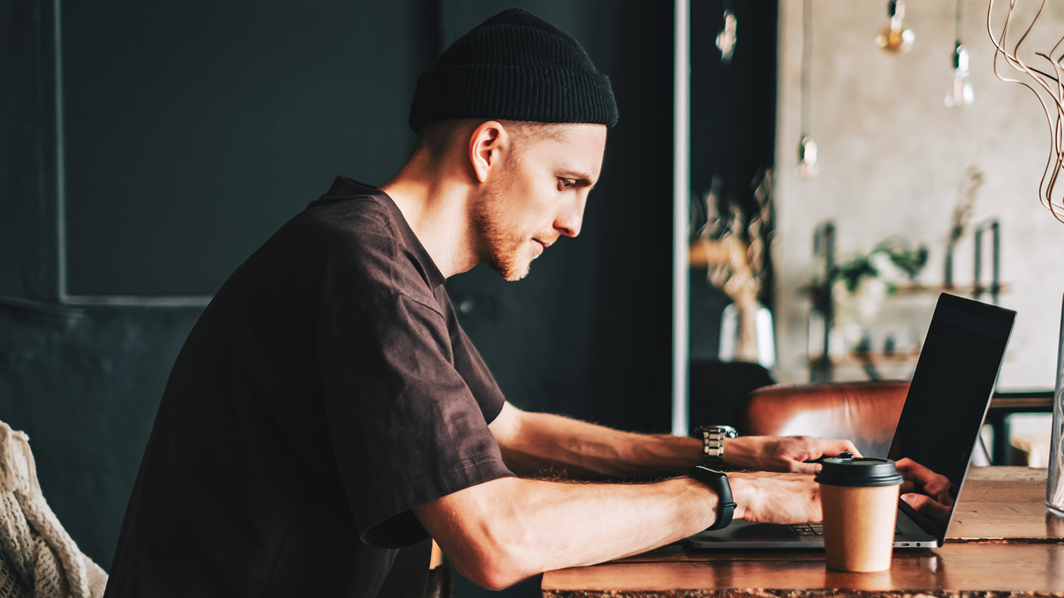 A hipster sitting at a table working on a laptop