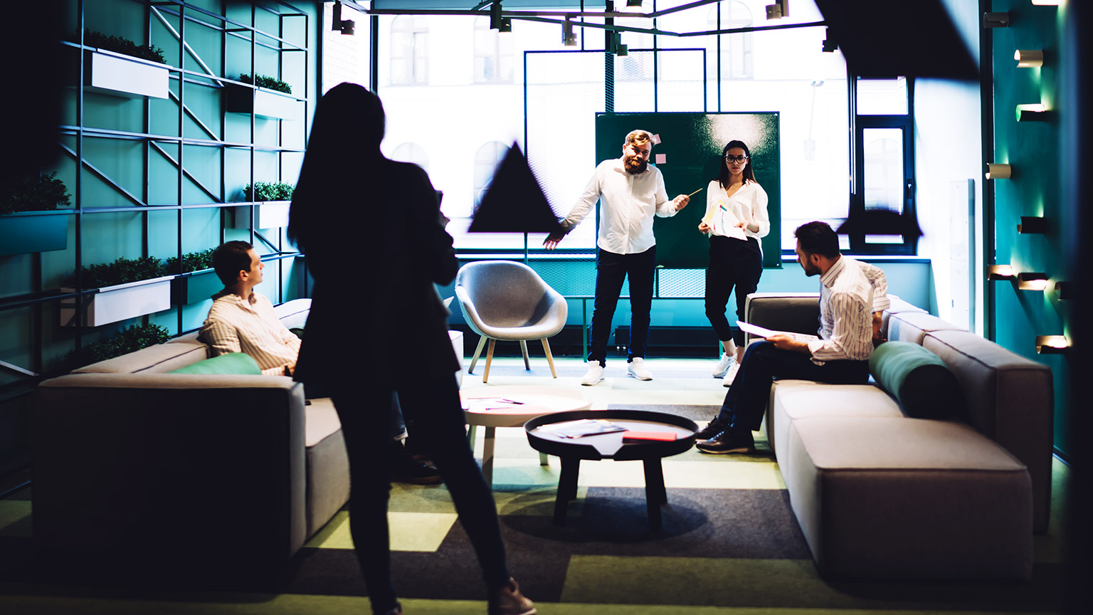 A small team discussing company development strategies in modern conference room with a whiteboard