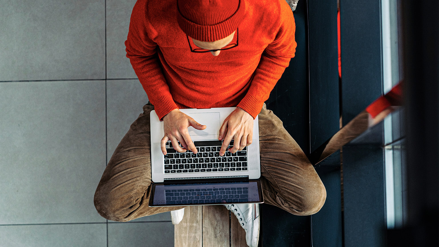 A top-down view of a developer sitting cross-legged, nursing their laptop and working on the front-end of a website