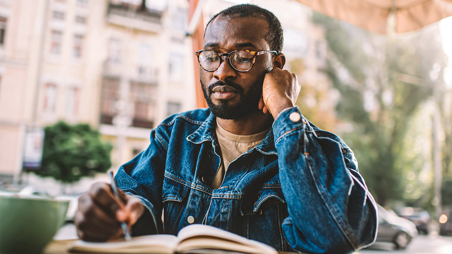 A professional seated outside, referencing documentation relating to their work