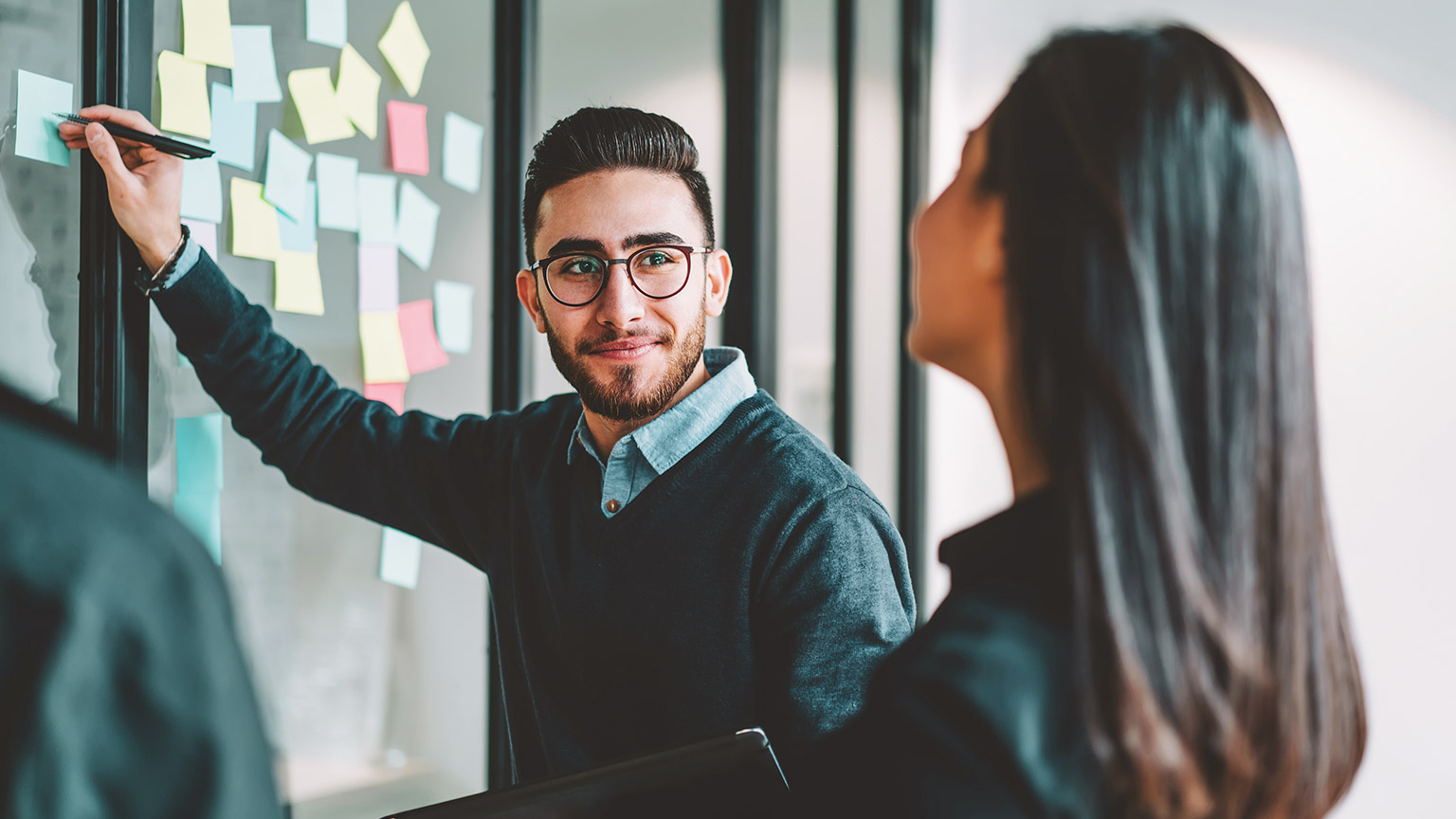 A manager brain-storming with their team on a glass window