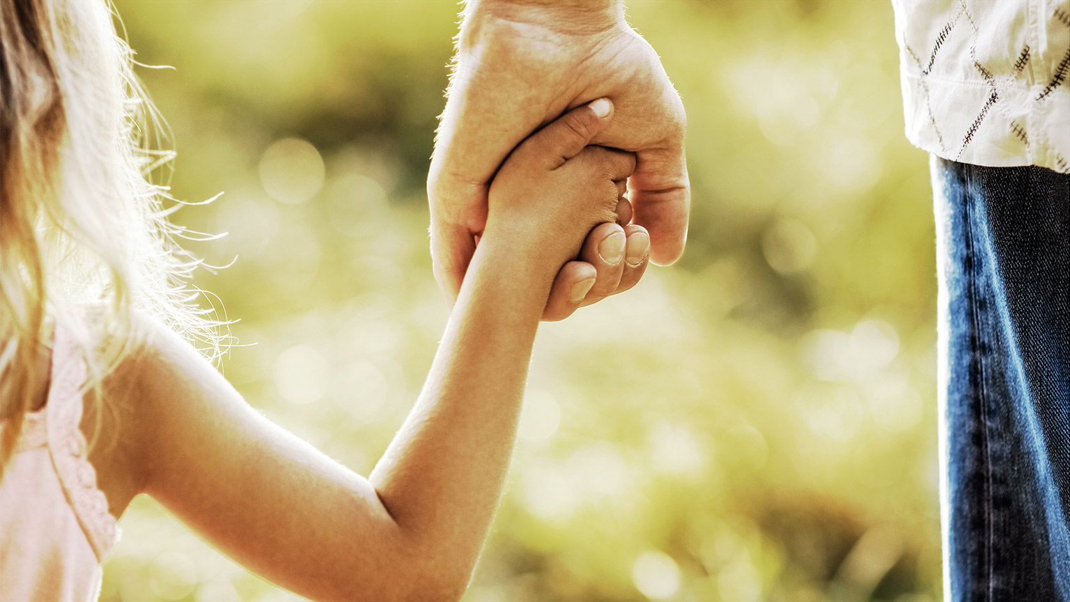 a child clinging to an adults hand