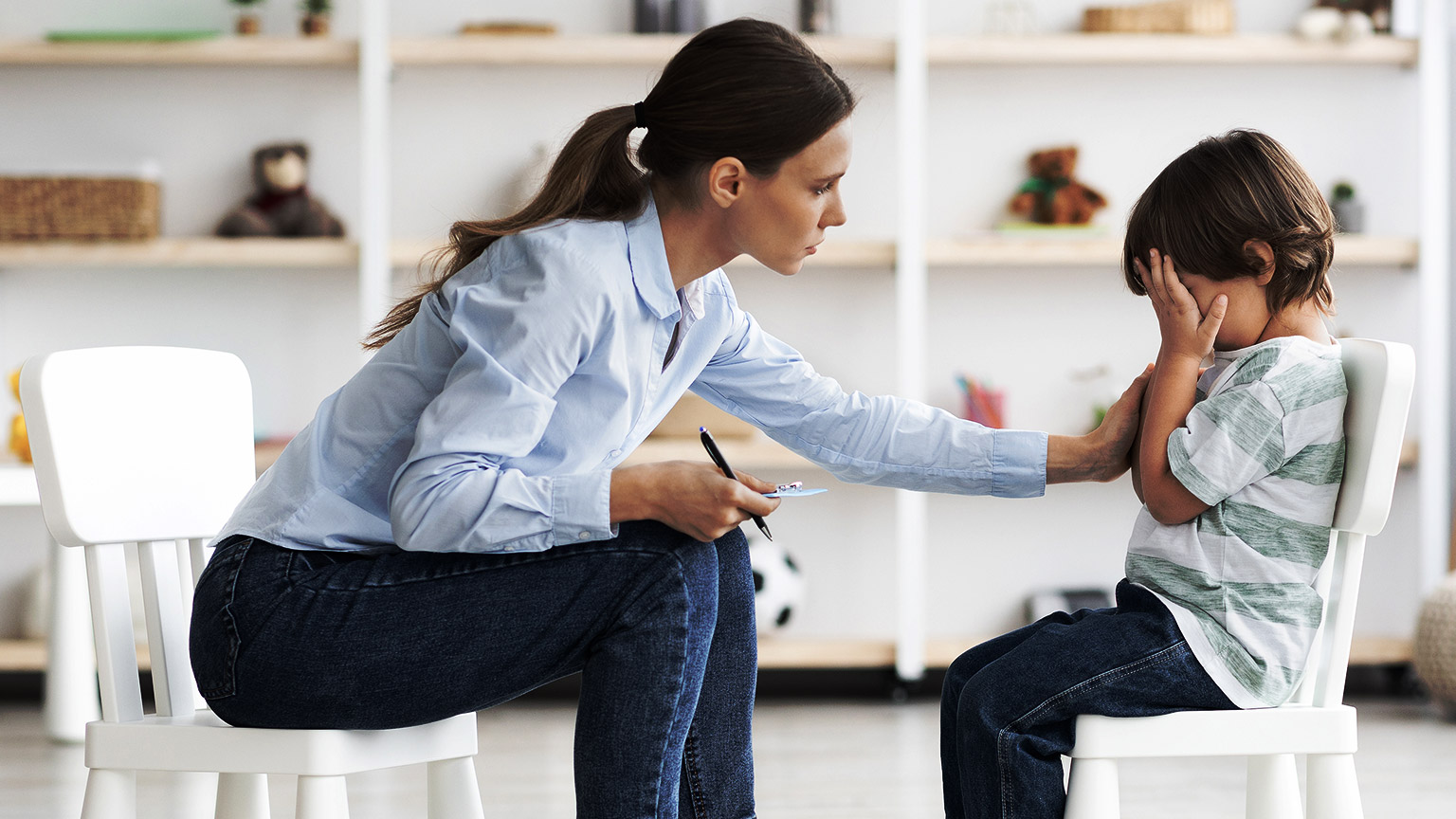 A child care professional interacting with a child that is visibly upset