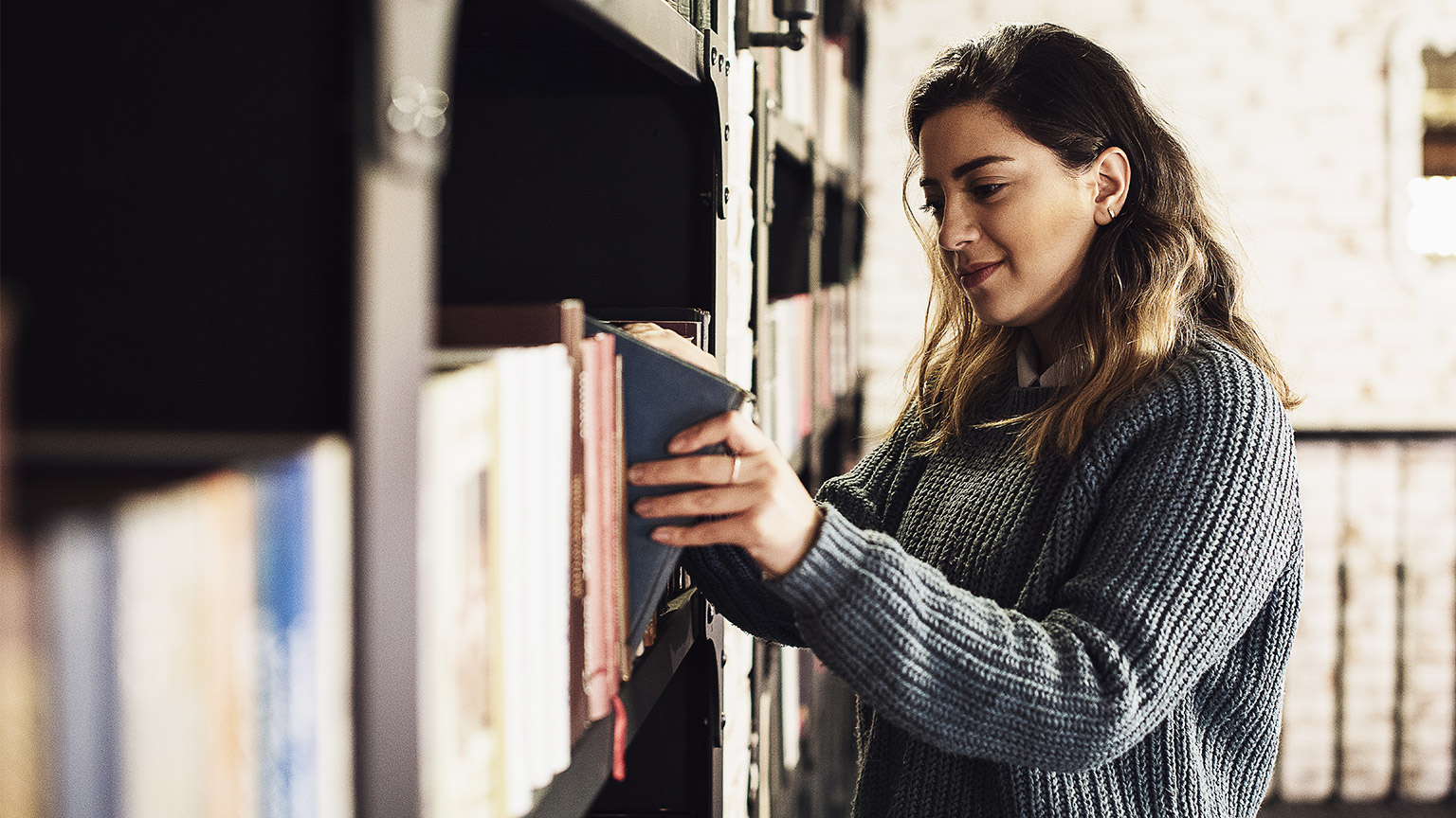 A student taking a book from a shelf in the library