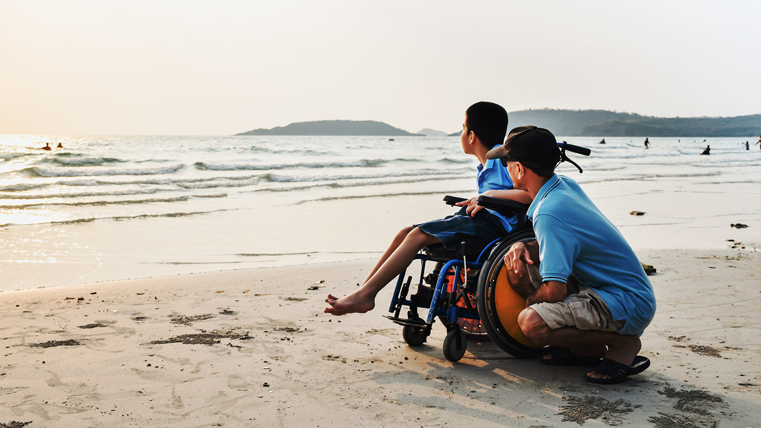 A person with disability on a beach with their carer