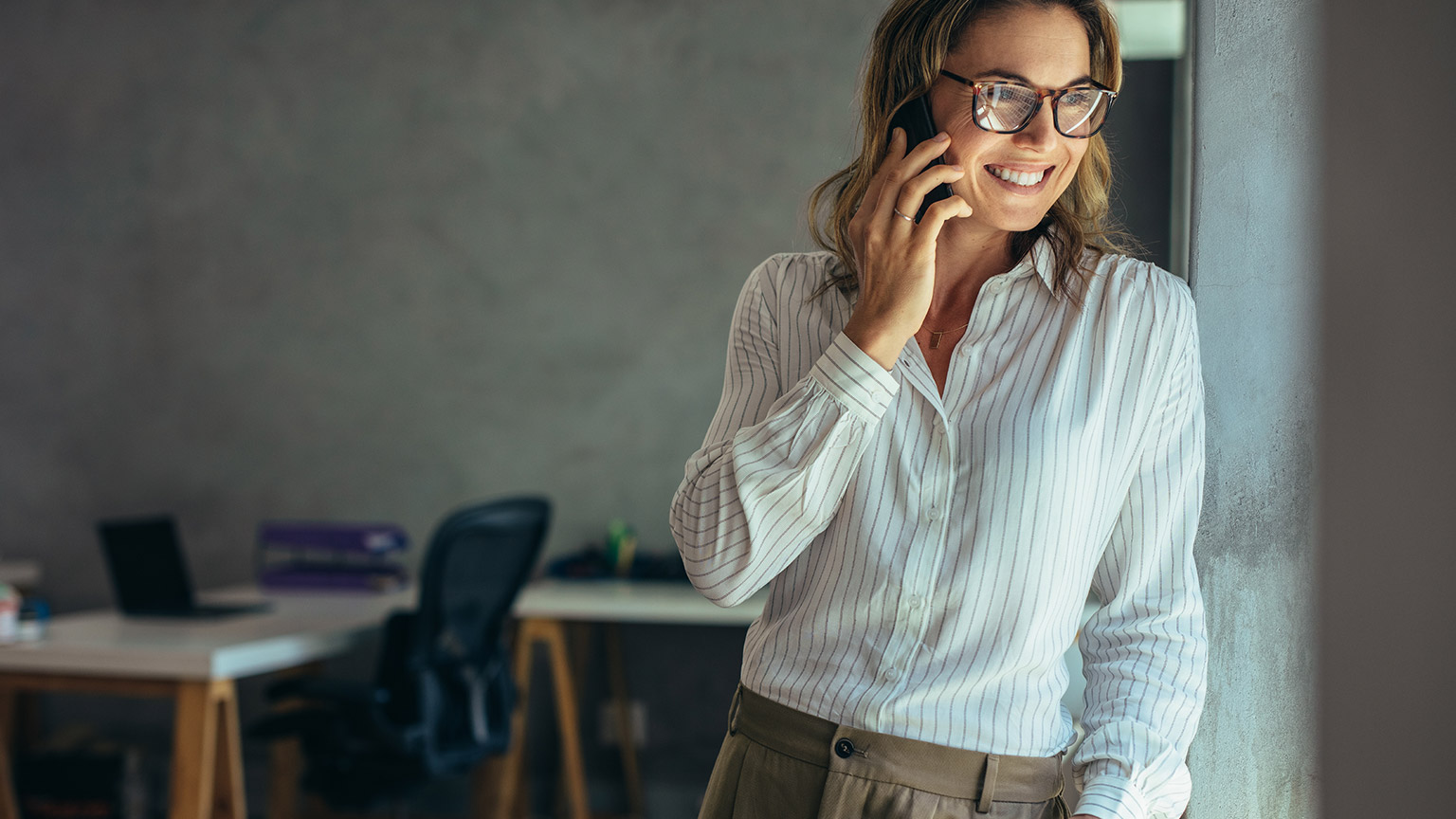 A confident entrepreneur talking on a mobile phone in a modern office space