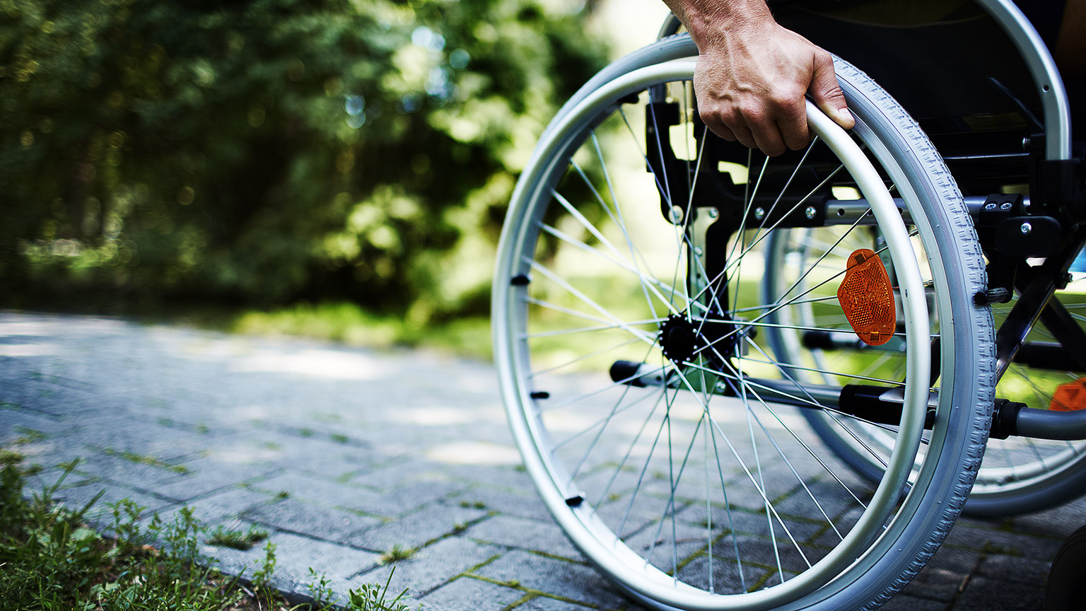 A person pushing themselves along the footpath in a wheelchair