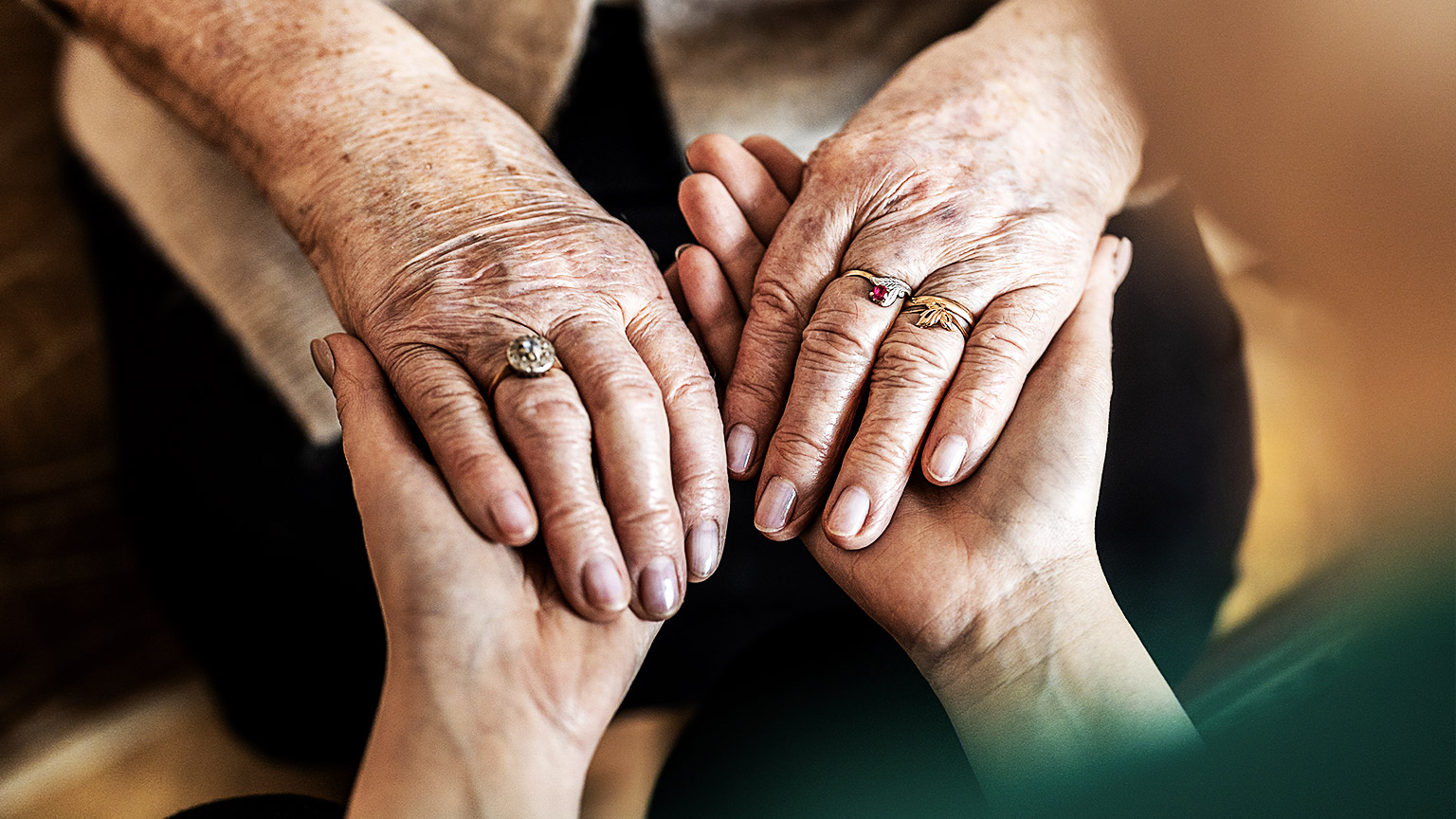 hands of an ageing person being held up by a younger pair of hands