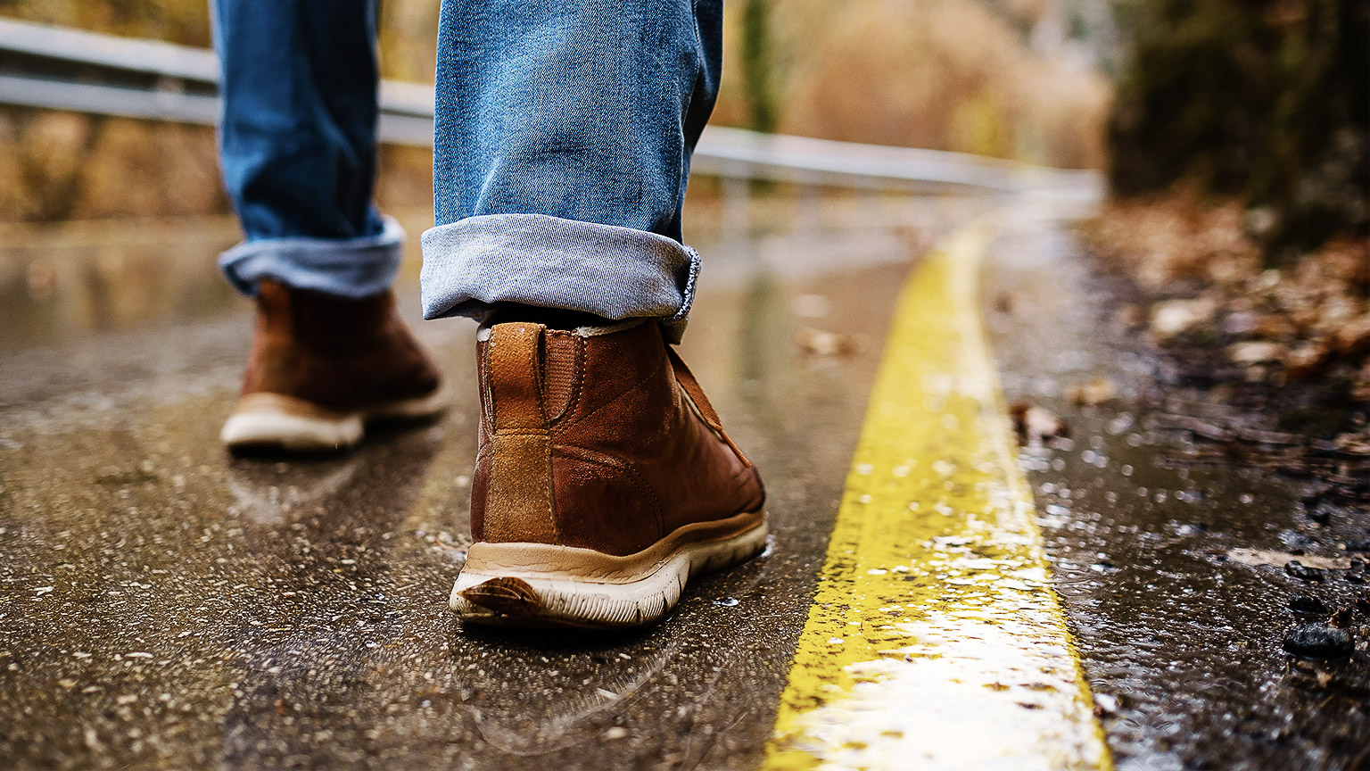 A close up of a person's feet walking down a quiet road