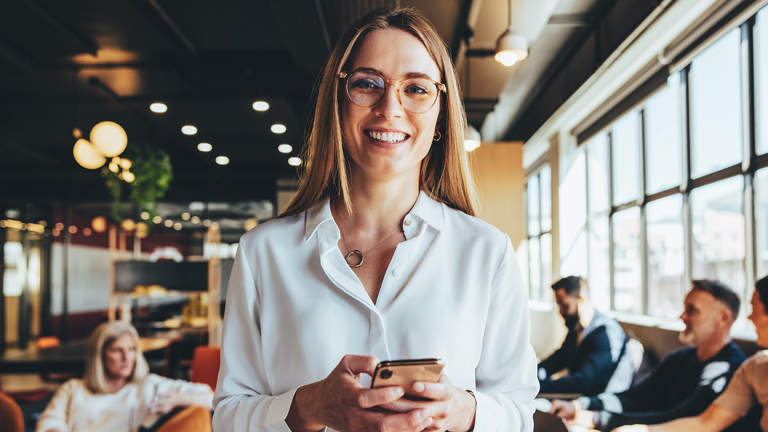 An entrepreneur standing in a modern office space with coworkers in the background