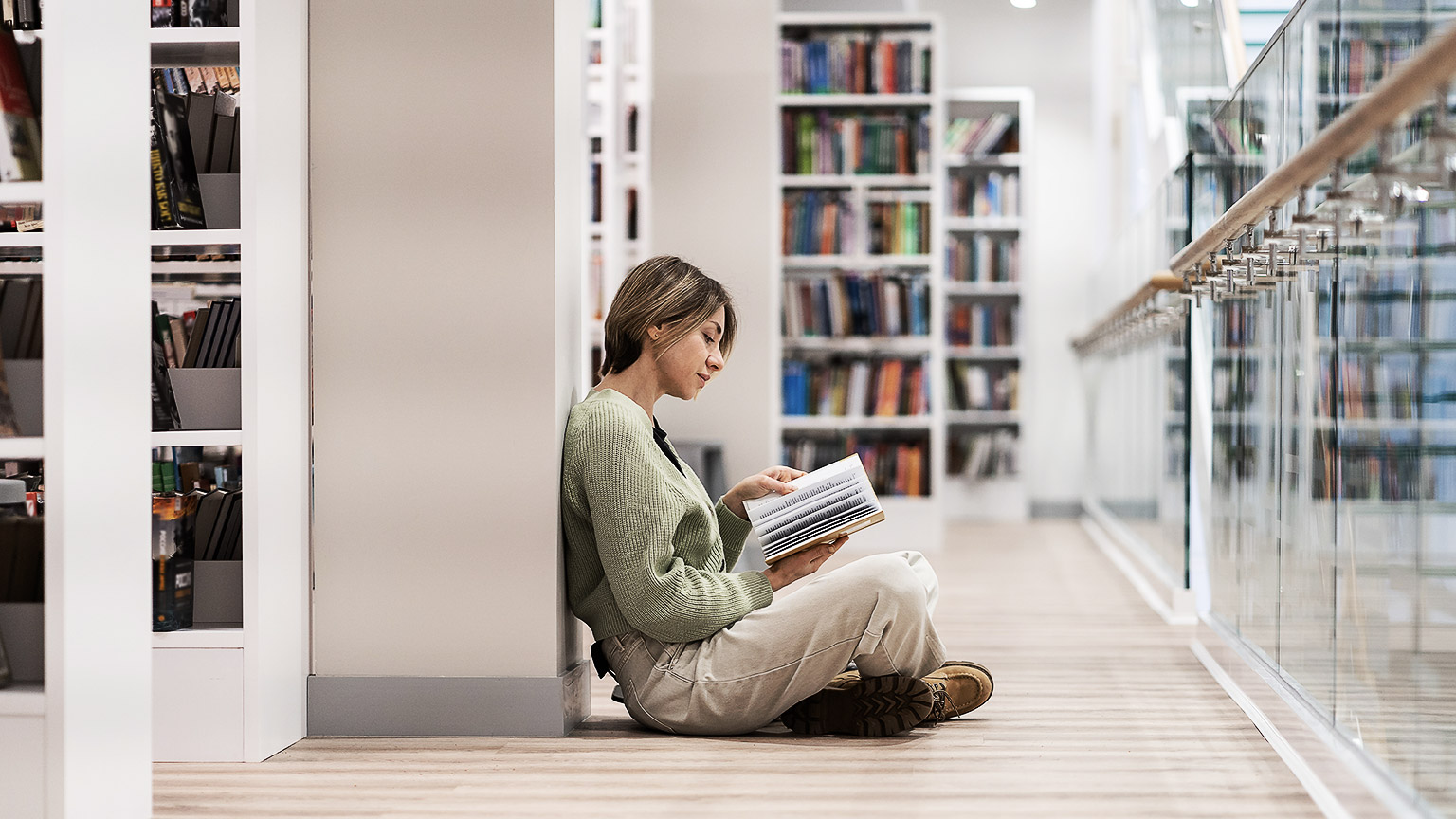 A person studying intently in a library while sitting on the floor