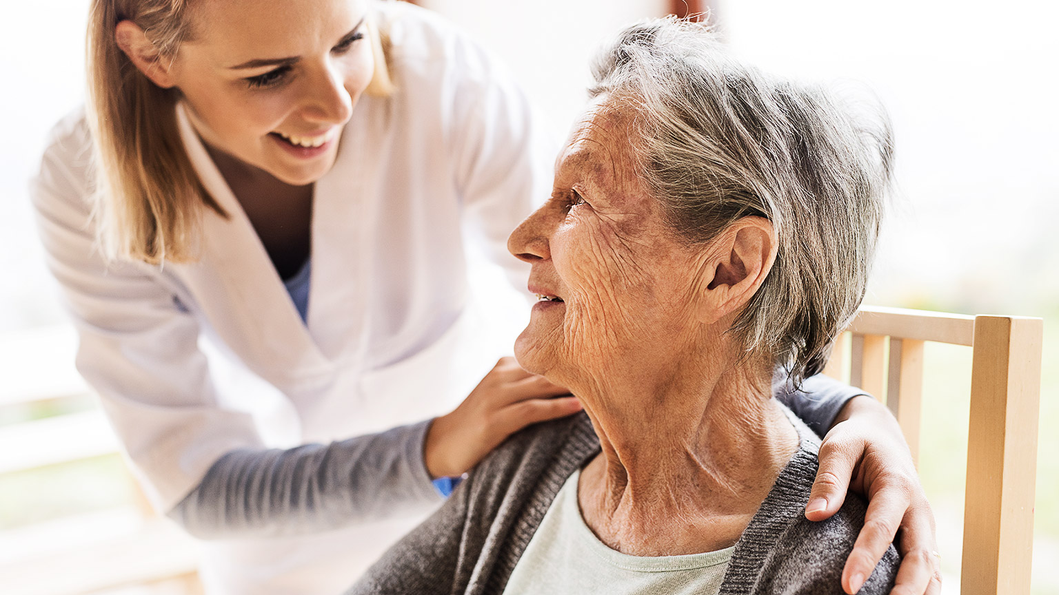 A career with their hands place on an elderly person's shoulders 