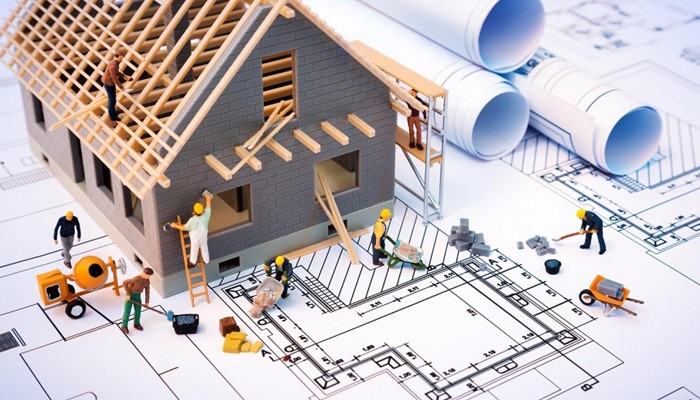 Construction workers building a house with plans in the background