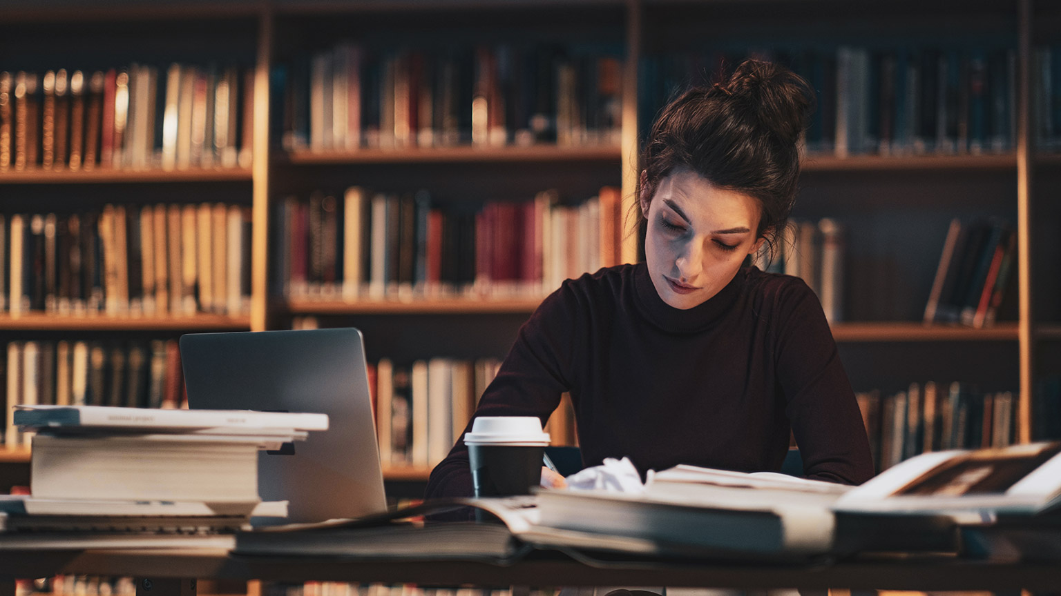 A student sitting in a library reading reference material