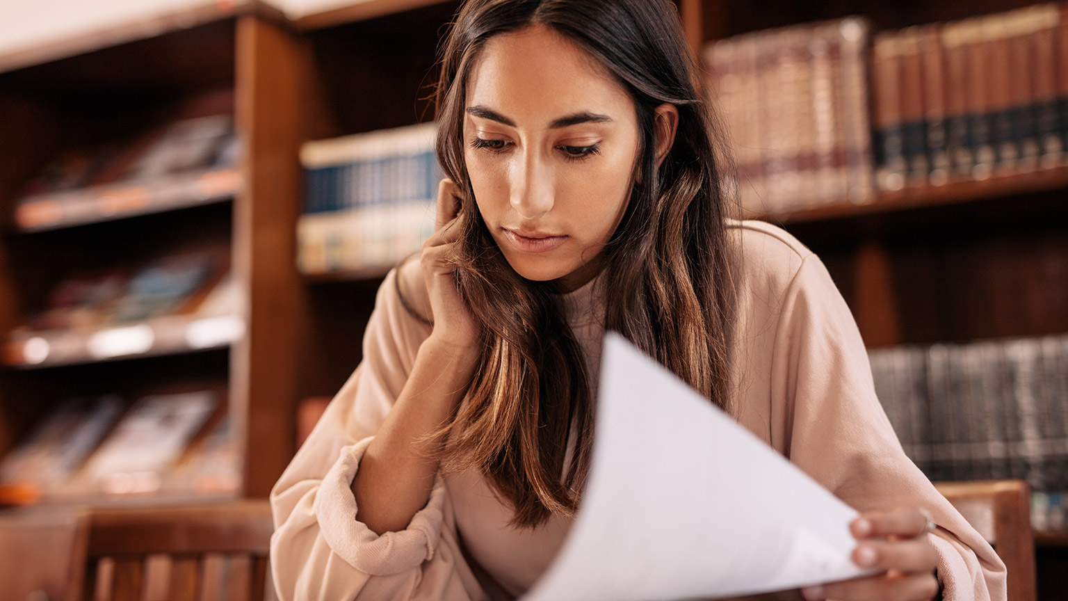 A close view of a student reading learning materials in a library setting