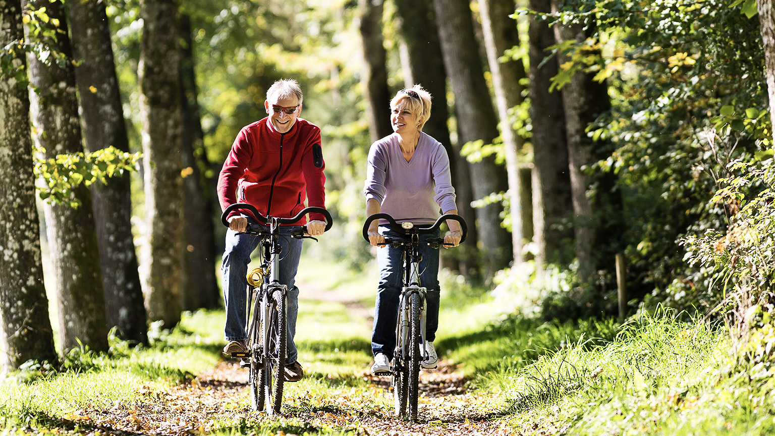 Two older people riding a bike and being active