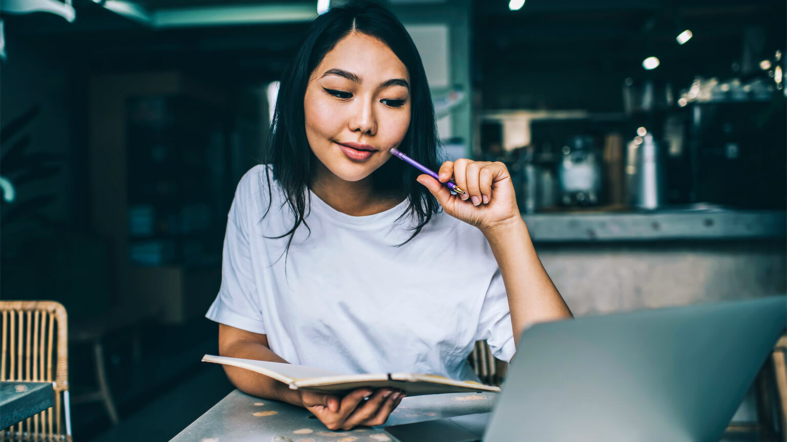 A student seated at a table, studying remotely, absorbing their learning materials