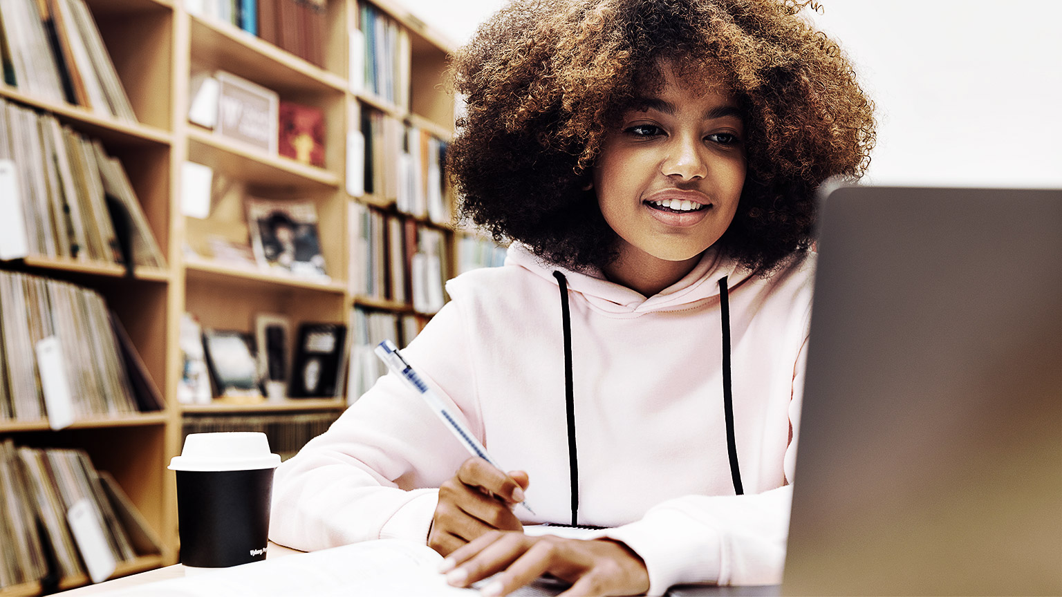 A person in a hoodie researching in a library