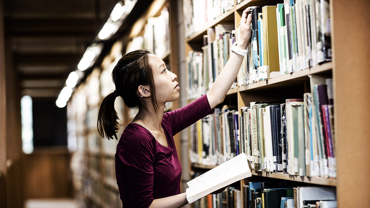 A person getting books from the library shelves