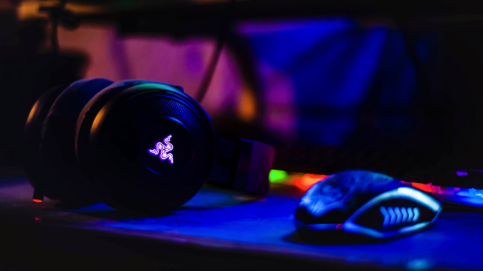 A close view of gaming headphones sitting on a desk in a dark room