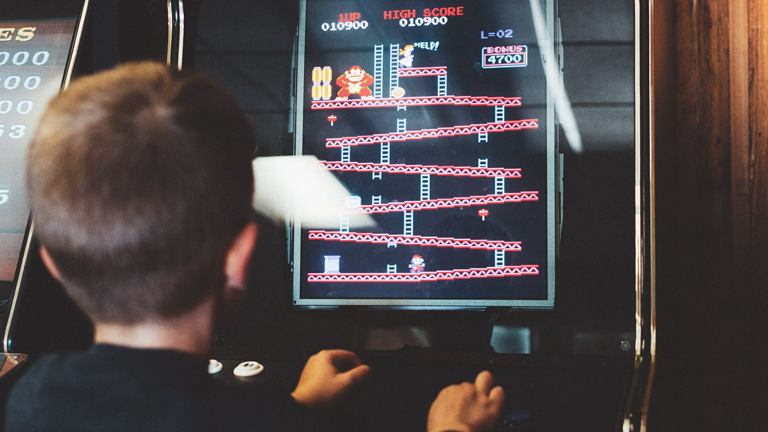 An over-the-shoulder view of a person playing an arcade game