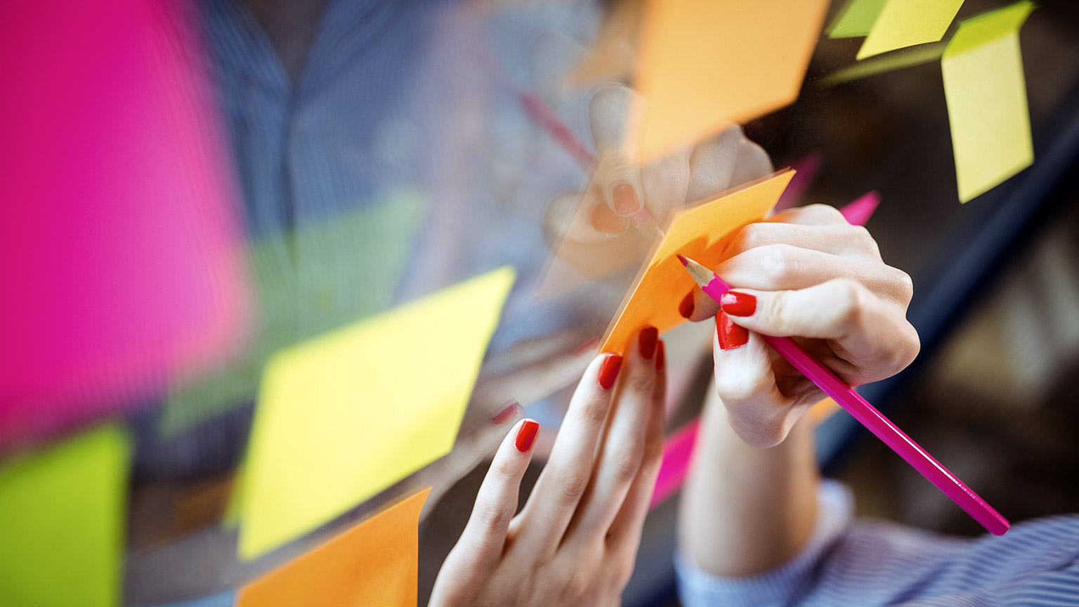 woman's hand writing on sticky note