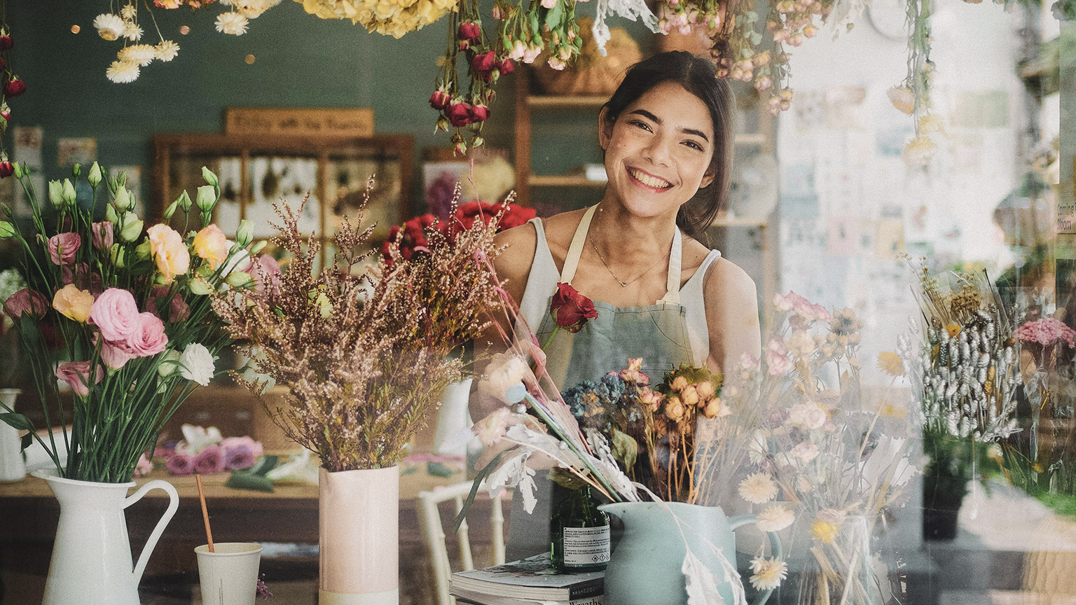 A small business owner standing in the window of their business