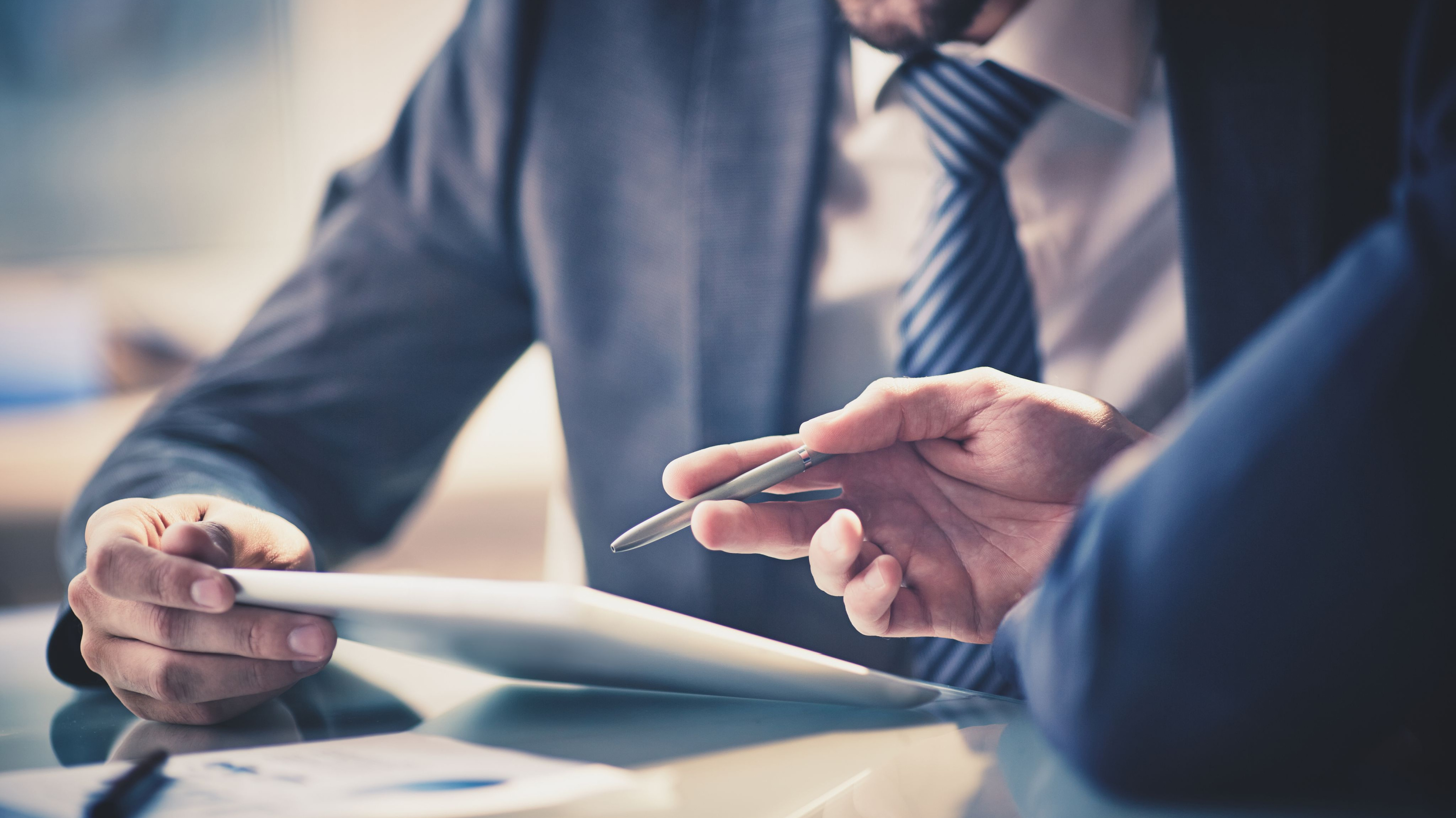 Image of two young businessmen using touchpad at meeting