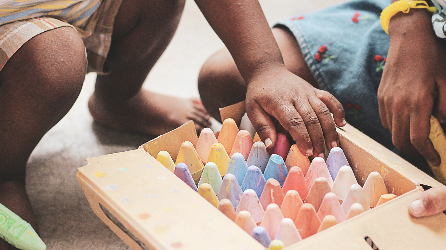 A close view of kids getting chalk sticks out of a container