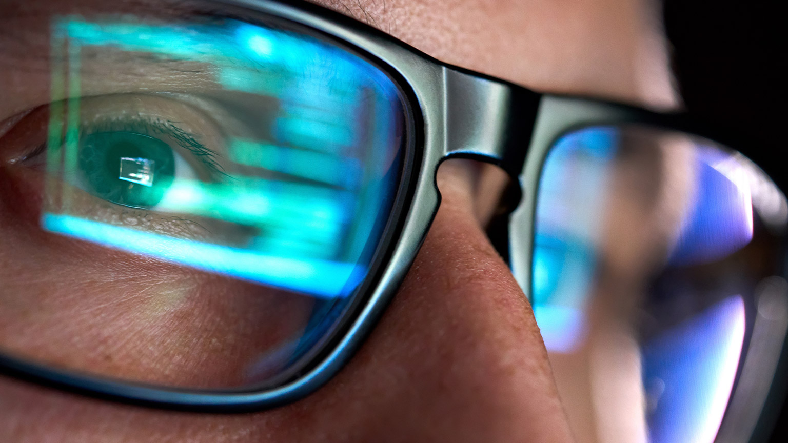 A close view of a programmer with code reflected in his glasses