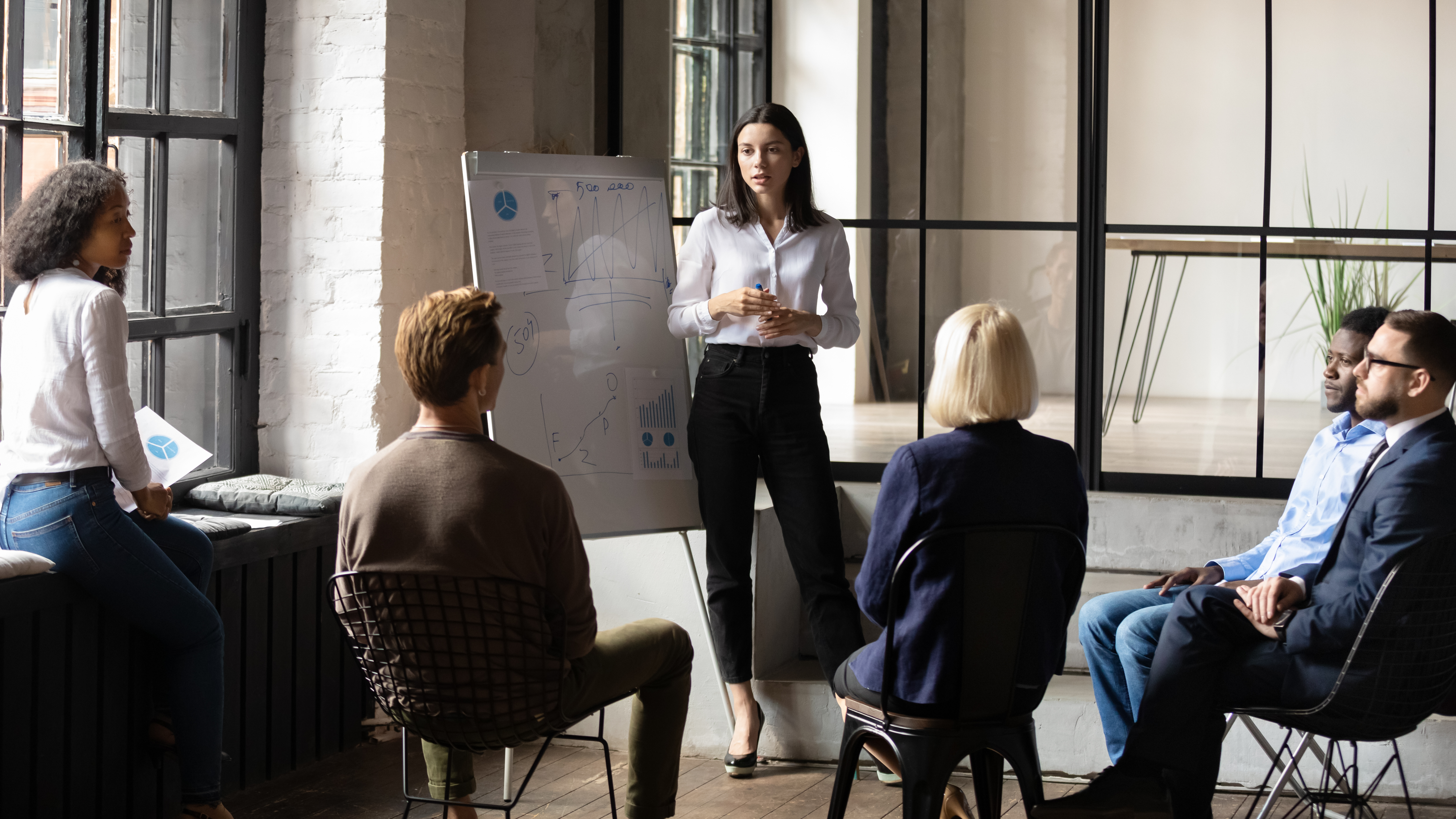 Confident female business leader give flip chart presentation consulting employees,  explaining strategy