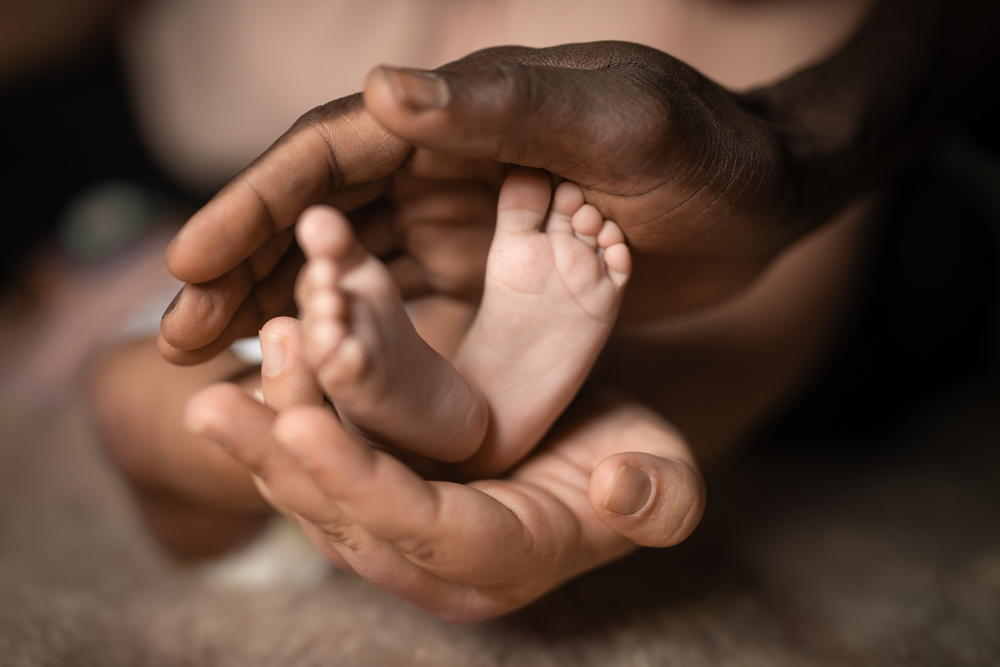 interracial family holding baby feet in hands mixed by black and white skin color