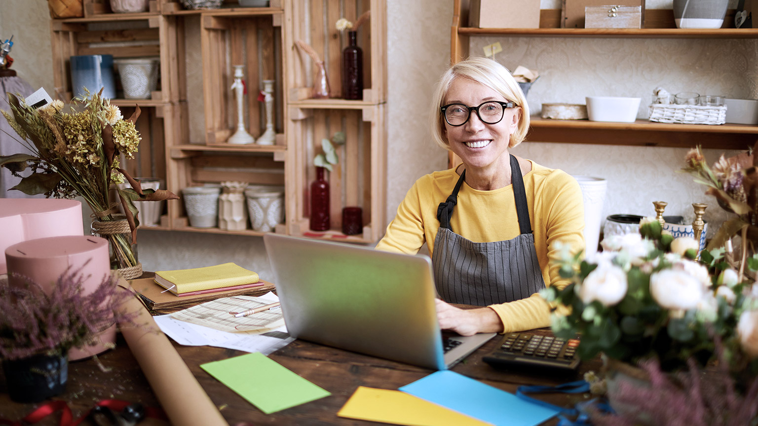 Flower business owner smiling with laptop and calculator