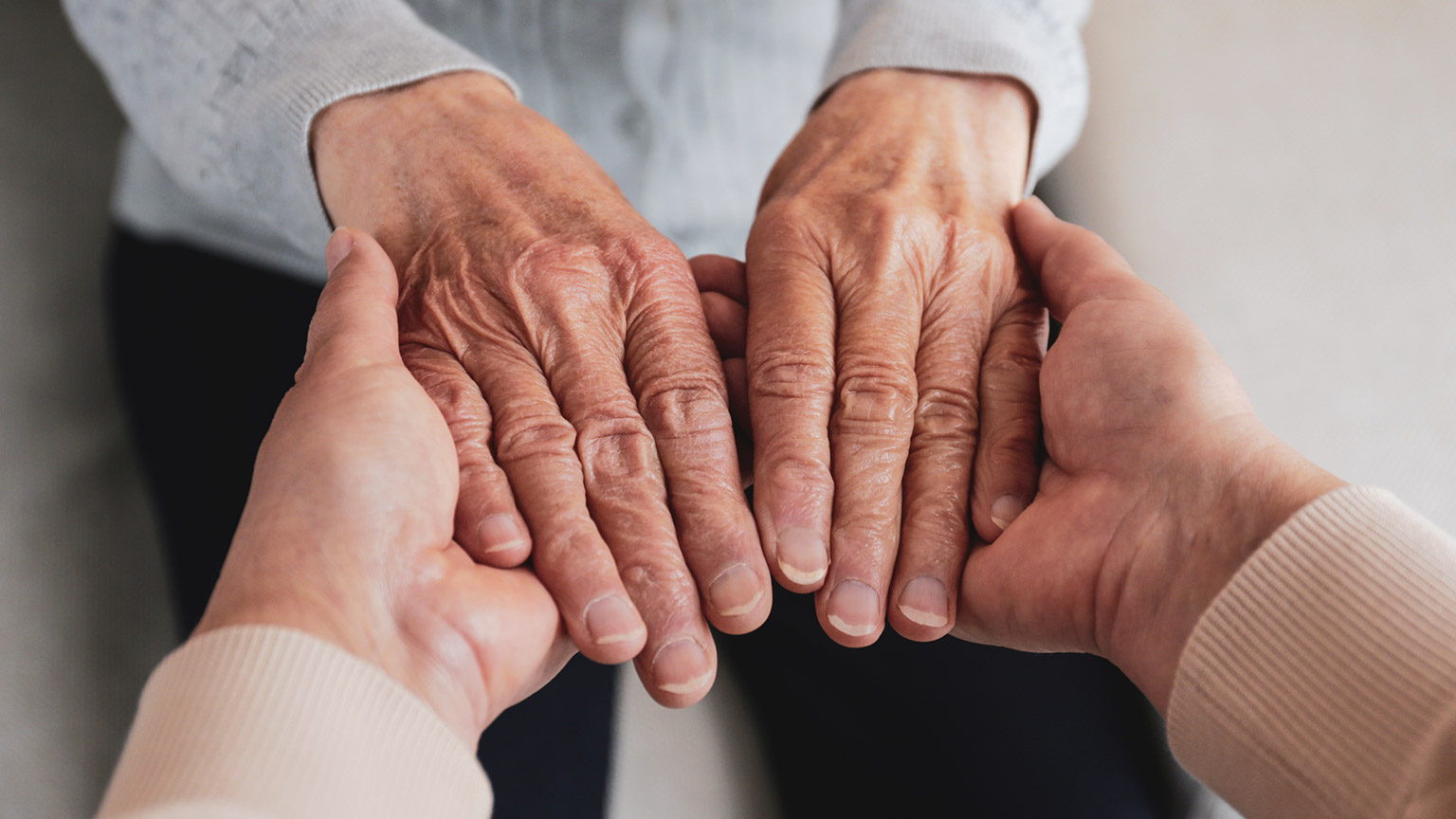 An aged care worker holding the hands of a client