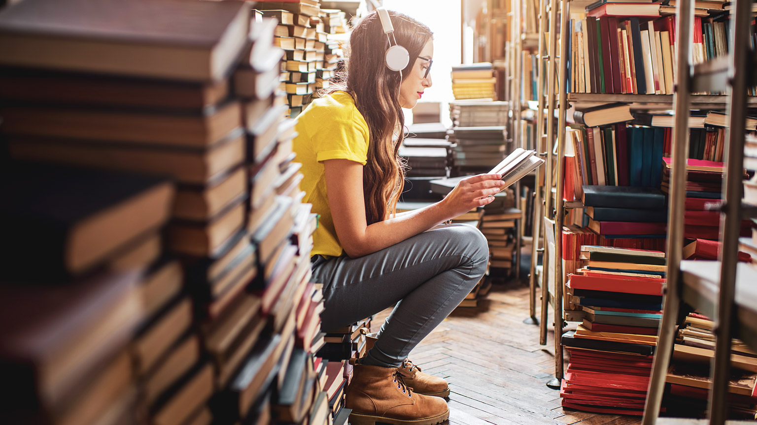 A student sitting in a library reading a book