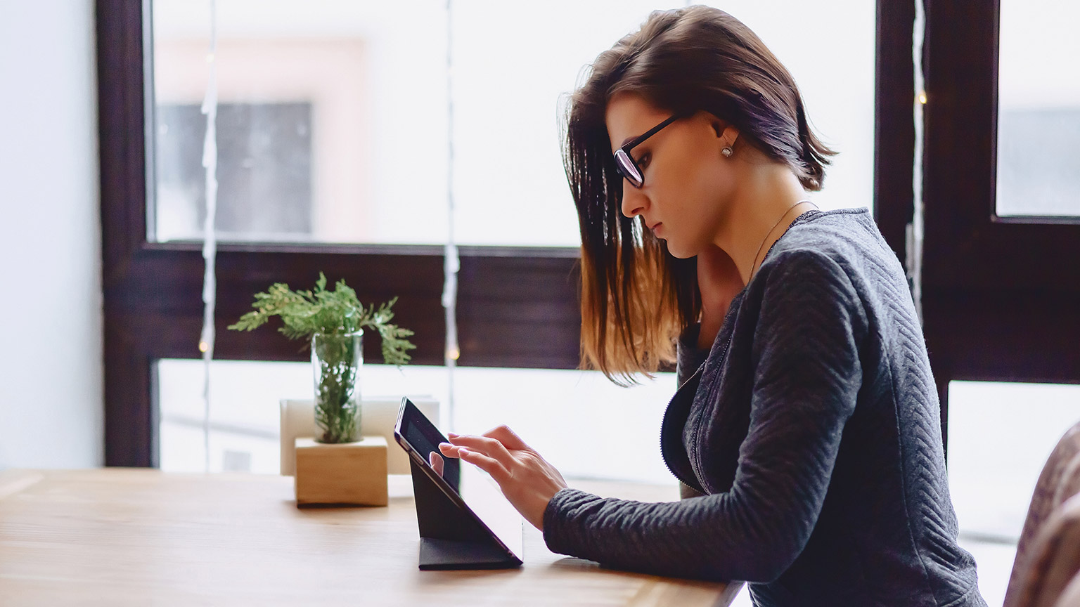 A person sitting at a table accessing resources on a tablet device