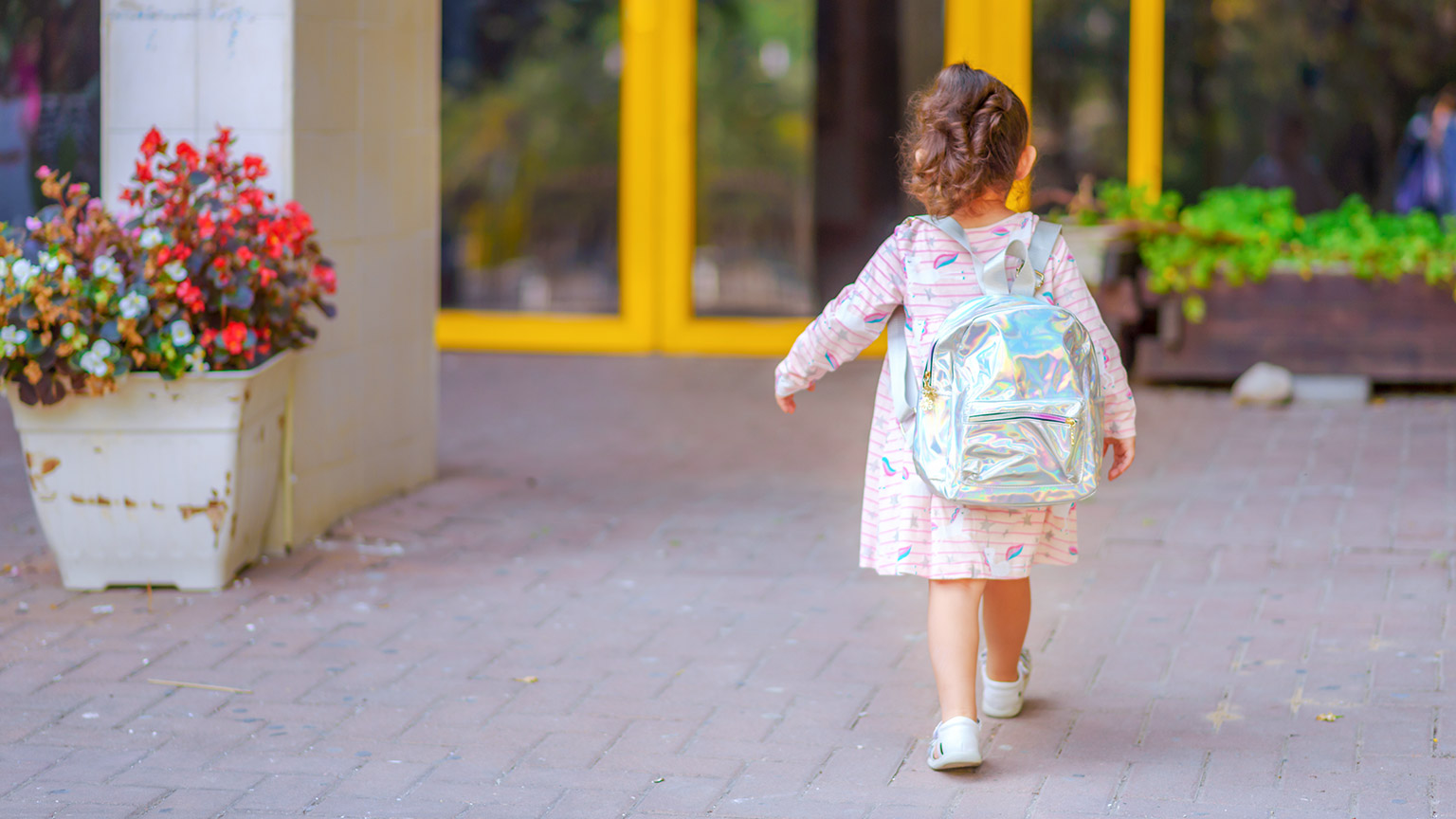 A young child wearing a backpack walking outside