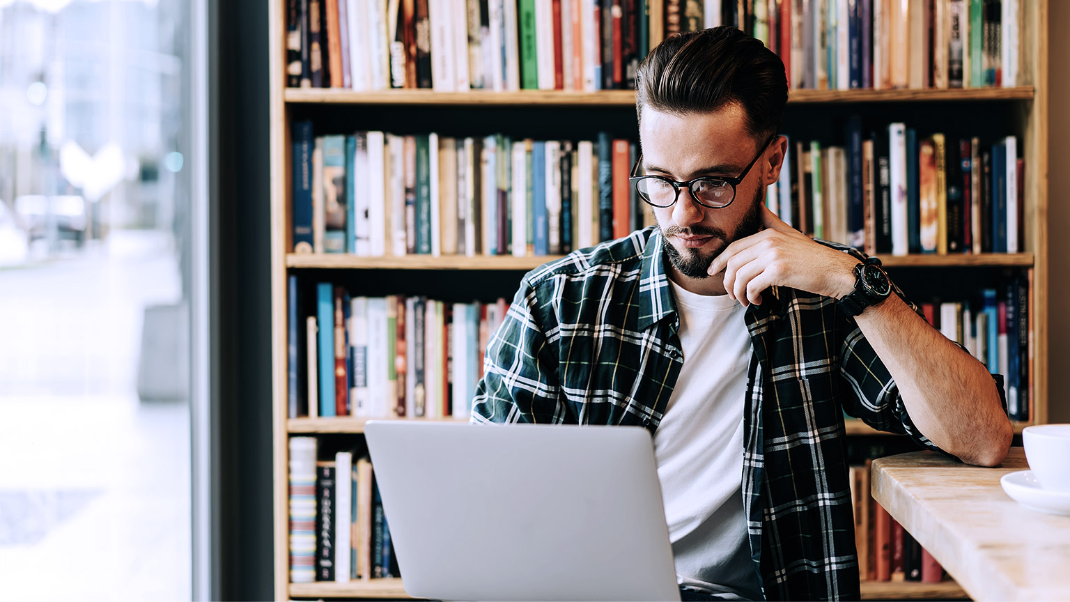 Hipster guy looking at computer inside the library