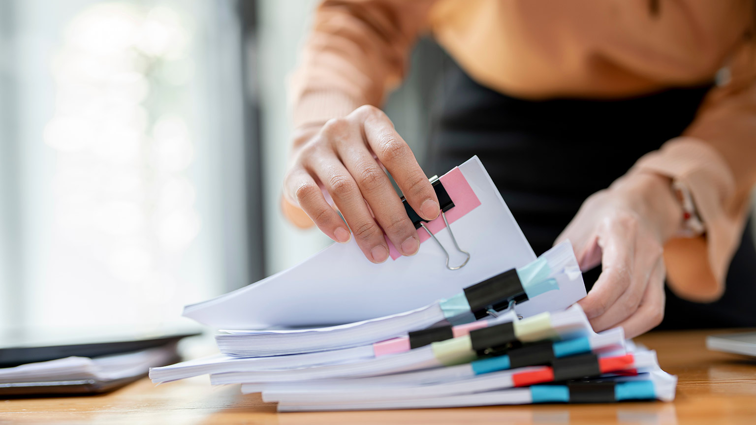 A close view of a person working through a large pile of paperwork