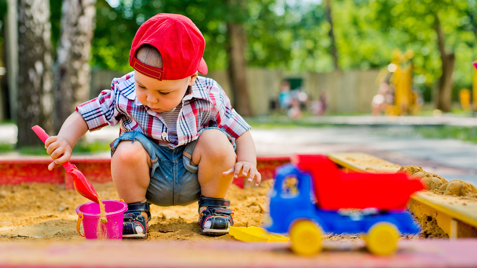 A small child playing in an outdoor sandbox